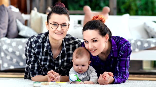 Two-pretty-casual-smiling-couple-woman-and-little-cute-child-posing-looking-at-camera