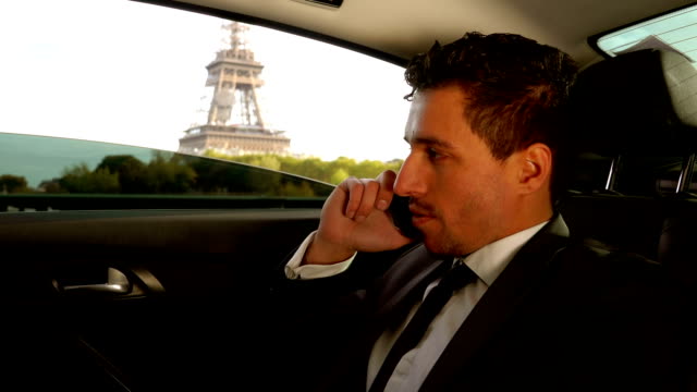 Attractive-young-man-in-a-suit-is-sitting-in-the-car-next-to-the-Eiffel-Tower