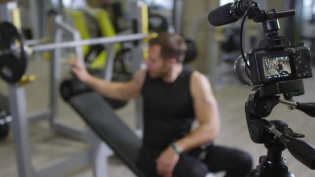 Gym-Coach-Explaining-Barbell-Exercise-on-Camera