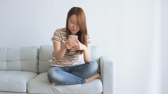 Mujer-asiática-usando-teléfono-celular-en-la-sala-de-estar