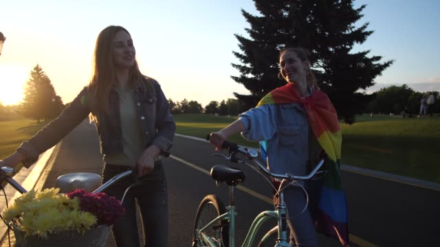 Attraktive-sschwules-Paar-sprechen-zu-Fuß-mit-Fahrrädern