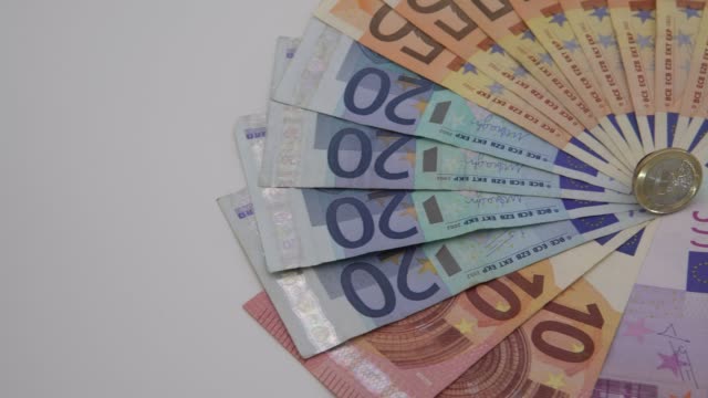 4K-Closeup-einer-Münze-einen-Euro-mit-Banknoten-mit-unterschiedlichen-Werten.-Bargeld