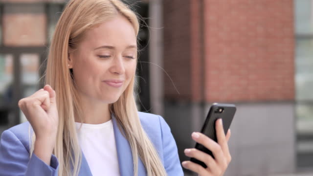 Young-Businesswoman-Celebrating-Win-on-Smartphone