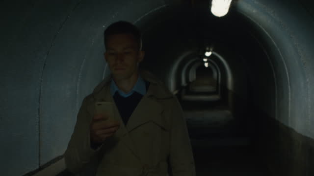 Ernster-Mann-mit-Handy-geht-durch-den-Tunnel
