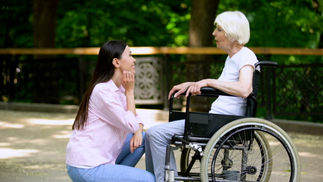 Voluntarios-sonrientes-hablando-con-una-anciana-en-silla-de-ruedas,-personas-discapacitadas-apoyan