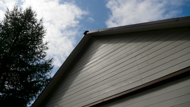 weißes-Haus-Holzdach-mit-schwarzem-Dach-mit-blauem-Himmel