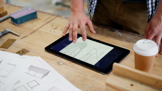 Close-up-of-male-hand-touching-tablet-screen-in-wood-workshop-indoors