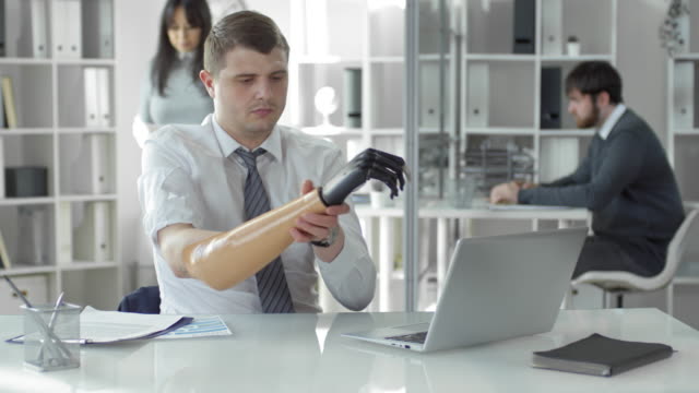 Businessman-Typing-on-Laptop-and-Putting-On-Prosthetic-Hand