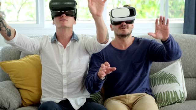 Schwules-Paar-entspannen-auf-der-Couch-mit-Virtual-Reality-Gerät.-Die-VR-Welt-erkunden.