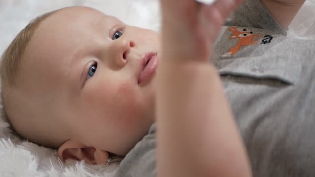 Nettes-Baby-hält-Telefon-in-den-Händen.-Das-Kind-spielt-mit-dem-Handy,-untersucht-es,-zerrt-in-seinen-Händen-und-versucht,-Smartphone-in-den-Mund-zu-nehmen