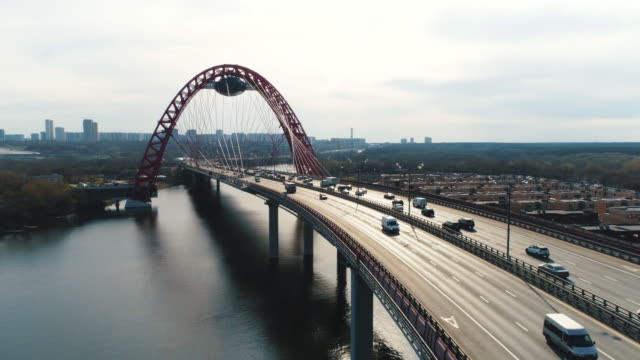 Luftaufnahme-der-modernen-Kabelbrücke-durch-den-Moskauer-Fluss-mit-fahrenden-Autos-gegen-wolkenverhangenen-Himmel.-Szene.-Moskauer-Skyline-im-Sommer