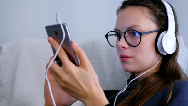 Woman-is-browsing-and-looking-in-social-media-in-smartphone-in-glasses-and-headphones.