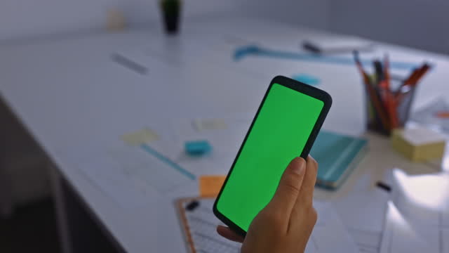 Geschäftsfrau-scrollt-durch-Smartphone-Greenscreen-in-ihrem-Büro