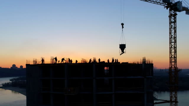 Aerial-shot-of-construction-site-with-cranes-and-workers-at-sunset