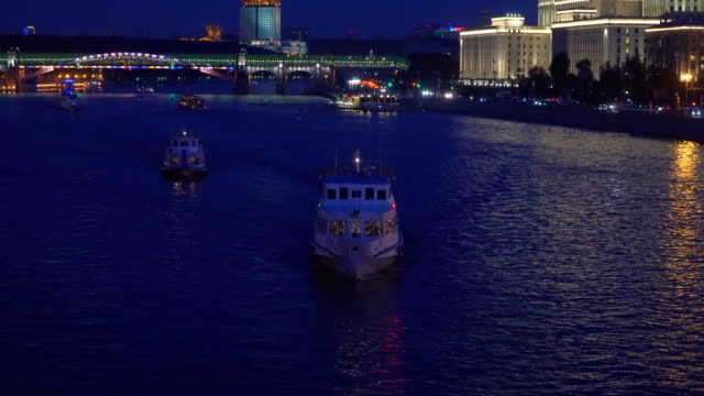 Nachtverkehr-von-Sportbooten-auf-einem-Fluss,-Stadt