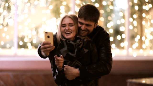 Young-happy-couple-take-selfie-photos-at-camera-on-smart-mobile-cell-phone