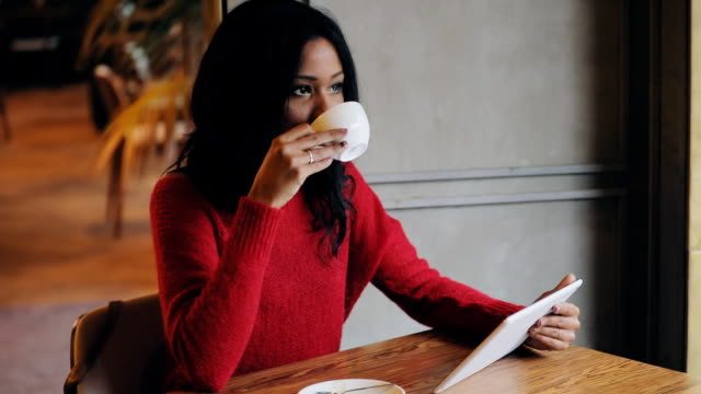 Mujer-con-tablet-pc-tomando-café-en-la-cafetería