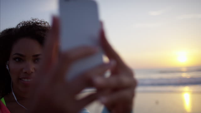Ethnic-African-American-female-taking-selfie-on-beach