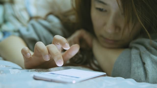 Woman-using-cellphone-in-bed-at-night