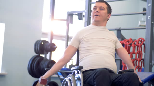 Training-session-of-a-disabled-man-with-two-dumb-bells-in-a-gym