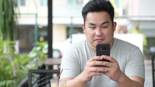 Junge-hübsche-Übergewicht-asiatischer-Mann-entspannend-im-Coffee-shop