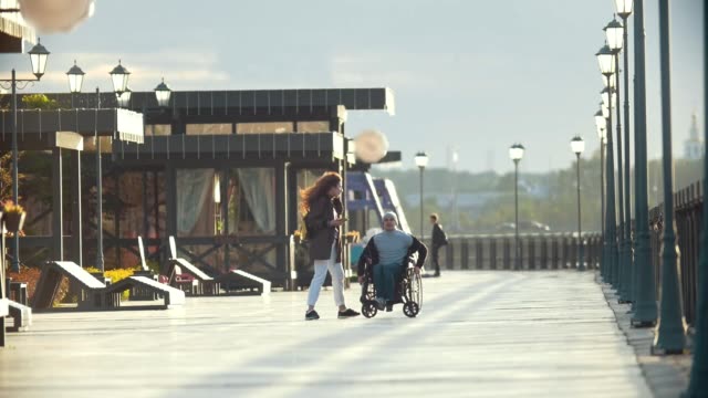 Hombre-discapacitado-en-silla-de-ruedas-toma-foto-de-mujer-joven-en-el-muelle
