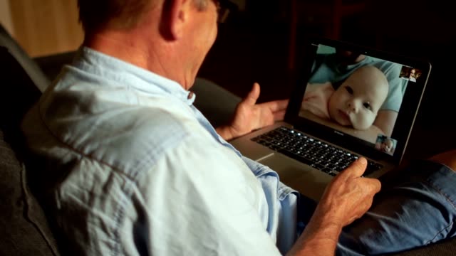 Un-hombre-maduro-habla-con-su-hijo-adulto-y-su-nieto-recién-nacido-en-Skype.-Comunicación-de-vídeo,-tres-generaciones-de-una-familia