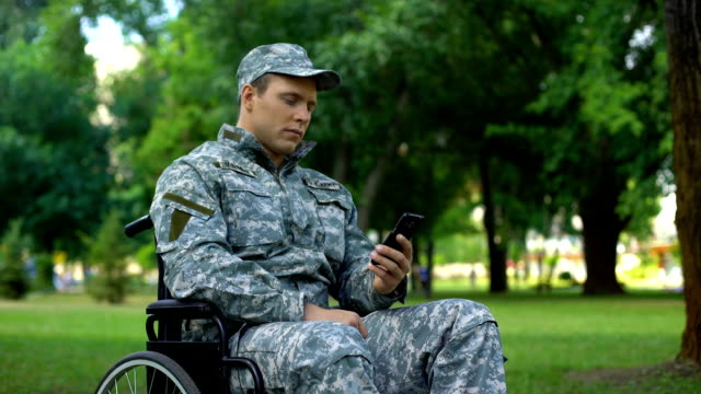 Disabled-male-in-uniform-scrolling-smartphone-application,-employment-service