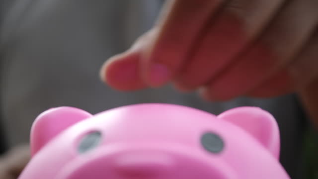 Hand,-setzen-Münzen-in-einem-Rosa-Sparschwein,-sparen-Geld-Konzept