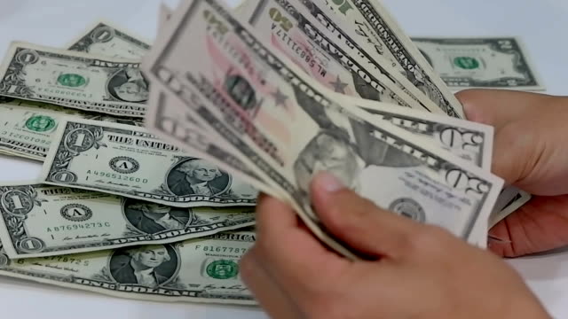 Das-Unternehmer-Hände-zählen-US-Dollar-Geldscheine-auf-weißem-Hintergrund.