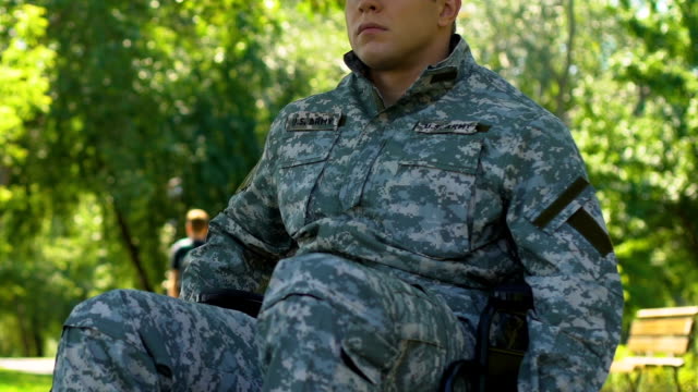 Man-in-military-uniform-sitting-in-wheelchair,-resting-enjoying-nature-in-park