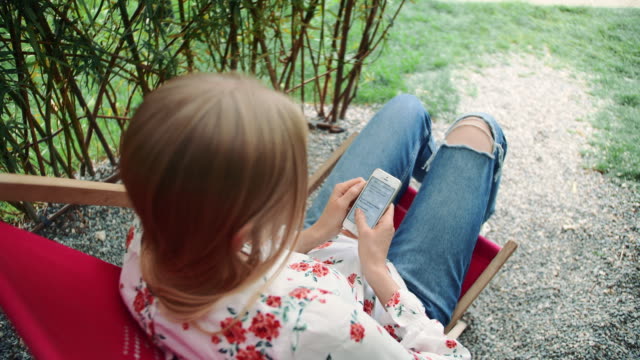 Young-woman-using-smartphone-in-plant-gazebo