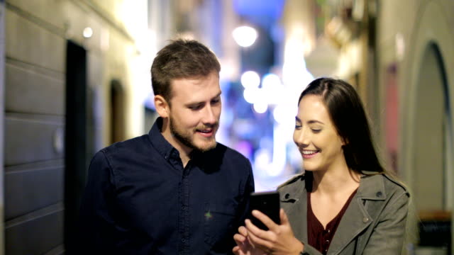 Happy-couple-browsing-phone-walking-in-the-night