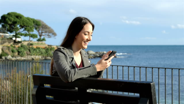 Mujer-feliz-con-un-teléfono-inteligente-en-la-playa