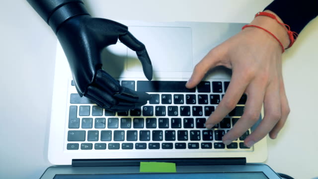 Prosthetic-and-a-healthy-hand-typing-on-the-keyboard.-Futuristic-human-cyborg-concept.