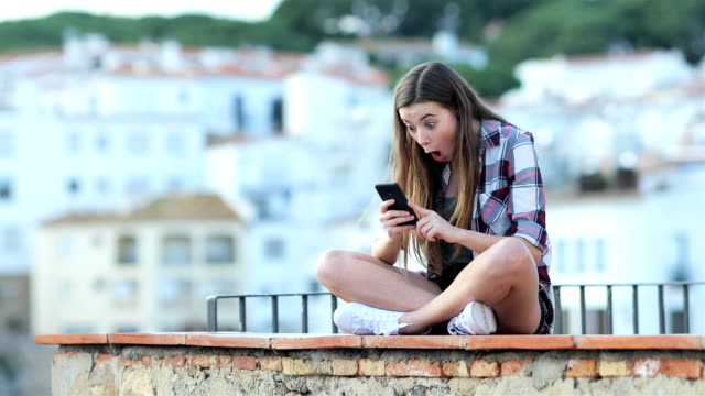 Teenager-Mädchen-Suche-nach-Online-Inhalten-auf-einem-Telefon-überrascht