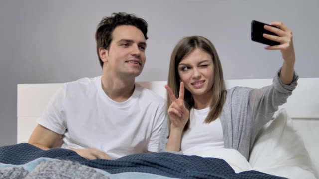 Glückliches-Paar-im-Bett-nehmen-Selfie-mit-Smartphone,-fotografieren