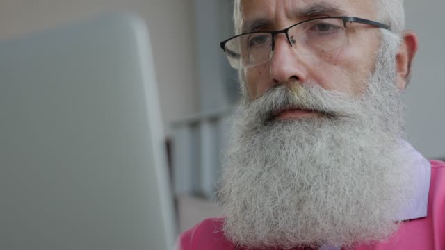 Senior-bearded-man-uses-laptop--in-cafe