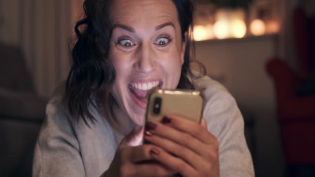Excited-woman-using-mobile-phone-at-night