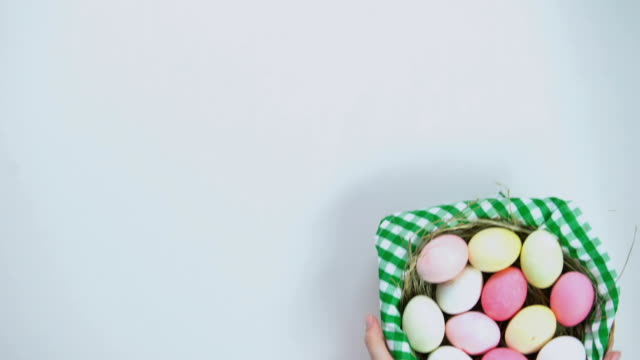 Happy-Easter-text,-woman-putting-basket-with-colored-eggs-on-white-background