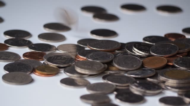 close-up-4k-motion-footage-of-money-coins-falling-to-pile-of-coins-on-white-floor.-business,-financial-for-money-saving-or-investment-concept