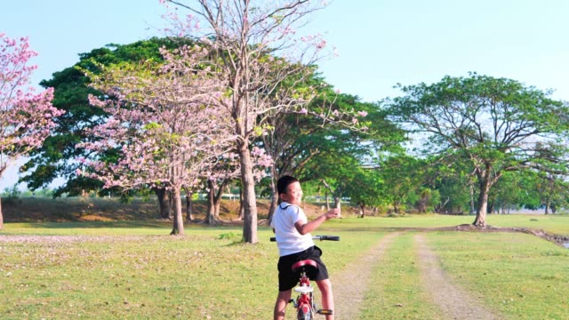 Eine-dicke-asiatische-Frau-joggt-abends-in-natürlichem-Sonnenlicht,-zusammen-mit-seinem-Sohn,-der-mit-dem-Fahrrad-unterwegs-ist.--Für-gute-Gesundheit.-Zeitlupe