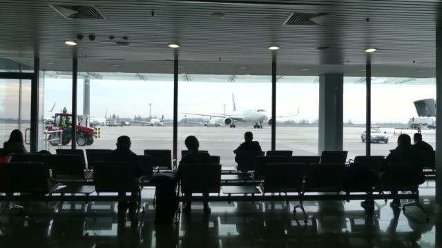 Passagiere-am-Flughafen-warten-auf-die-Einschiffung.-Passagiere-warten-auf-die-Landung-am-Flughafen.-Im-Hintergrund-ist-ein-Flugzeug.