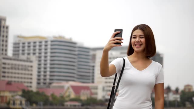 Schöne-junge-asiatische-Frau-mit-Video-Chat-mit-Smartphone-mit-Freunden-in-den-sozialen-Medien-Sommerurlaub.