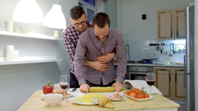 Un-par-de-hombres-gay-se-juntan-la-masa-de-pizza-abrazando.