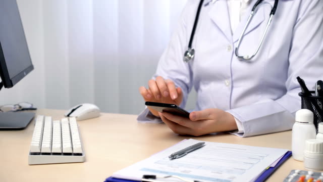 Arzt-mit-medizinischer-Anwendung-auf-Smartphone,-Texting,-Browserinformationen