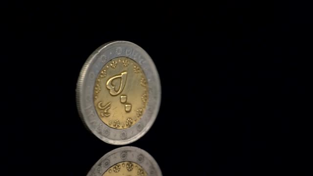 Moneda-de-500-riales-iraníes-girando-sobre-fondo-oscuro.