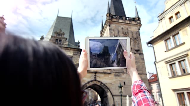 Weiblicher-Reisender,-der-mittelalterliche-Burg-und-blauen-Himmel-mit-Tablet-PC-über-der-Schulter-fotografiert