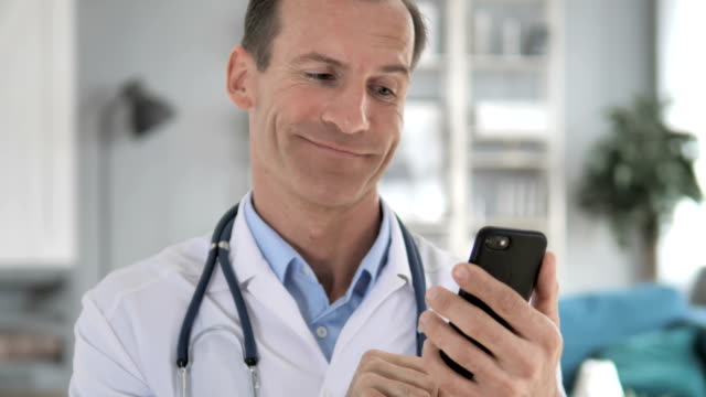 Senior-Doctor-Browsing-Internet-auf-Smartphone