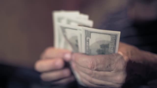 man-considers-cash-on-costs-,-male-hand-with-money-closeup,-planning-the-family-budget